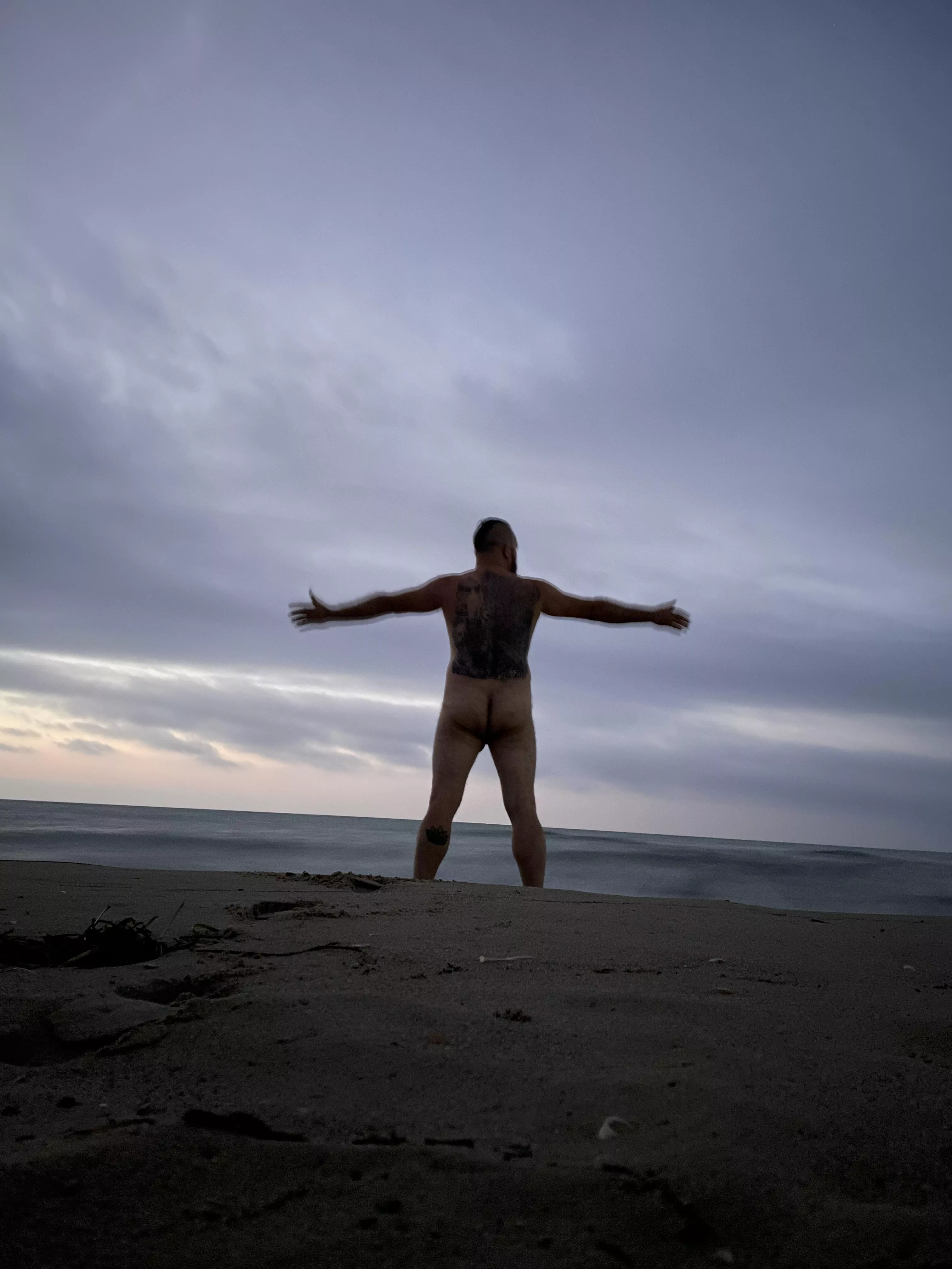 Bad inked and naked man at the beach.