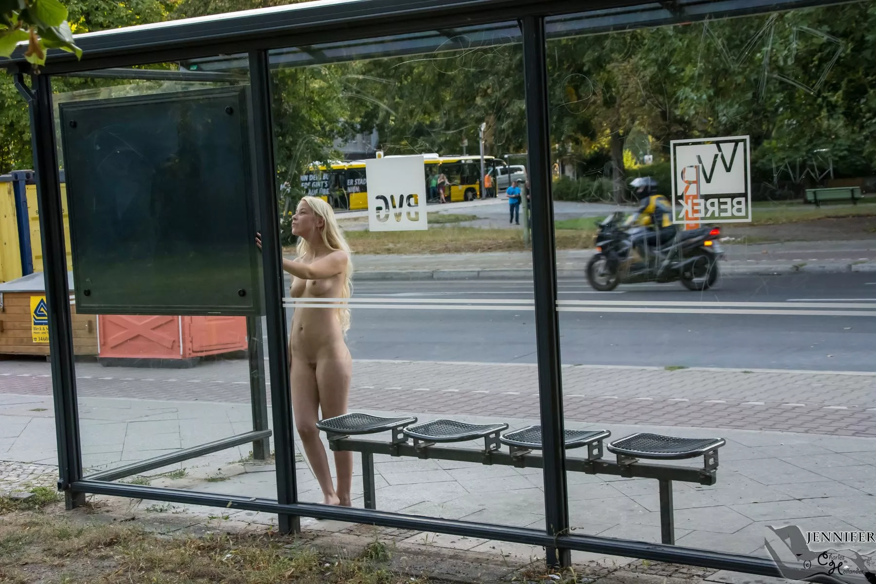 Jennifer reads the timetable at the bus stop. Nude in Berlin.