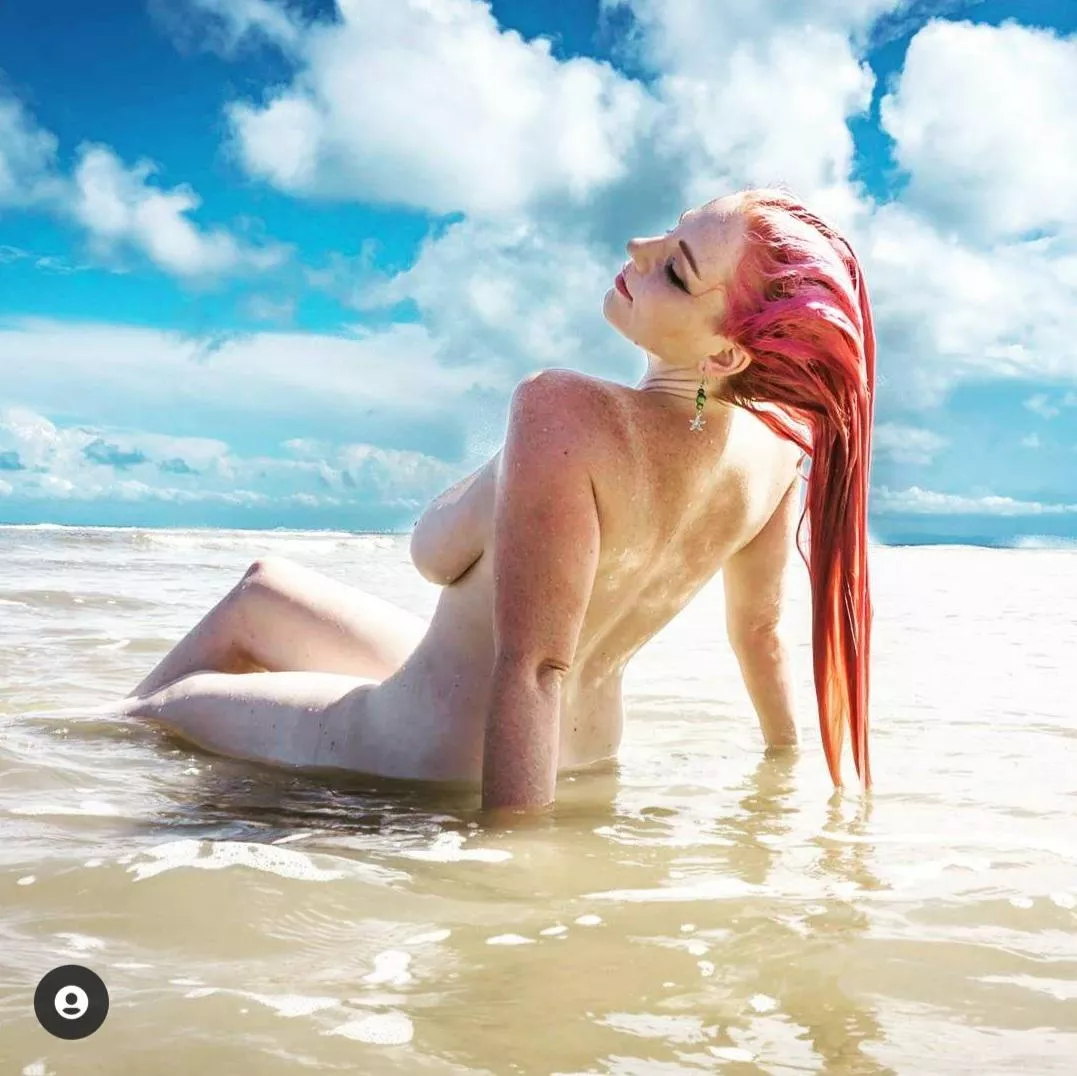 Long wet pink hair while reclining naked in the ocean