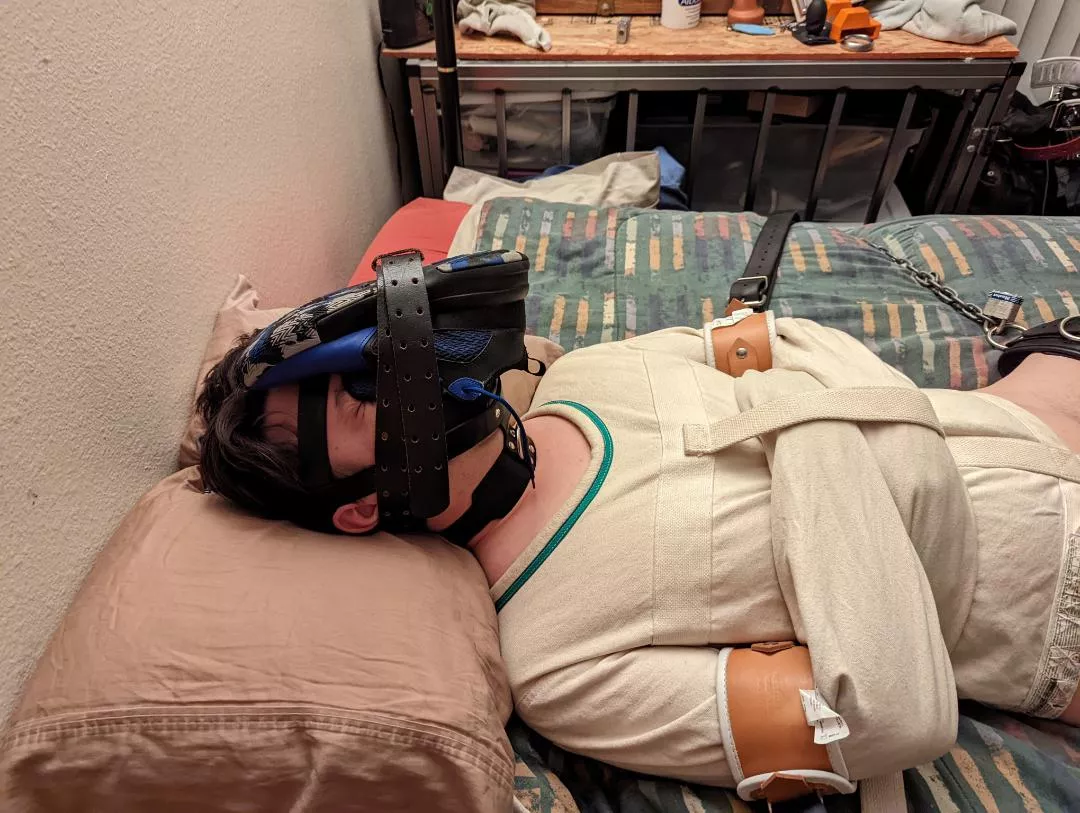 Straitjacketed, shoe strapped to his face, and bound to the bed.