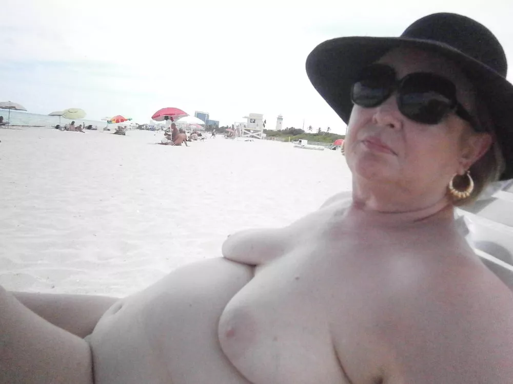 Plump older nudist relaxing on the beach