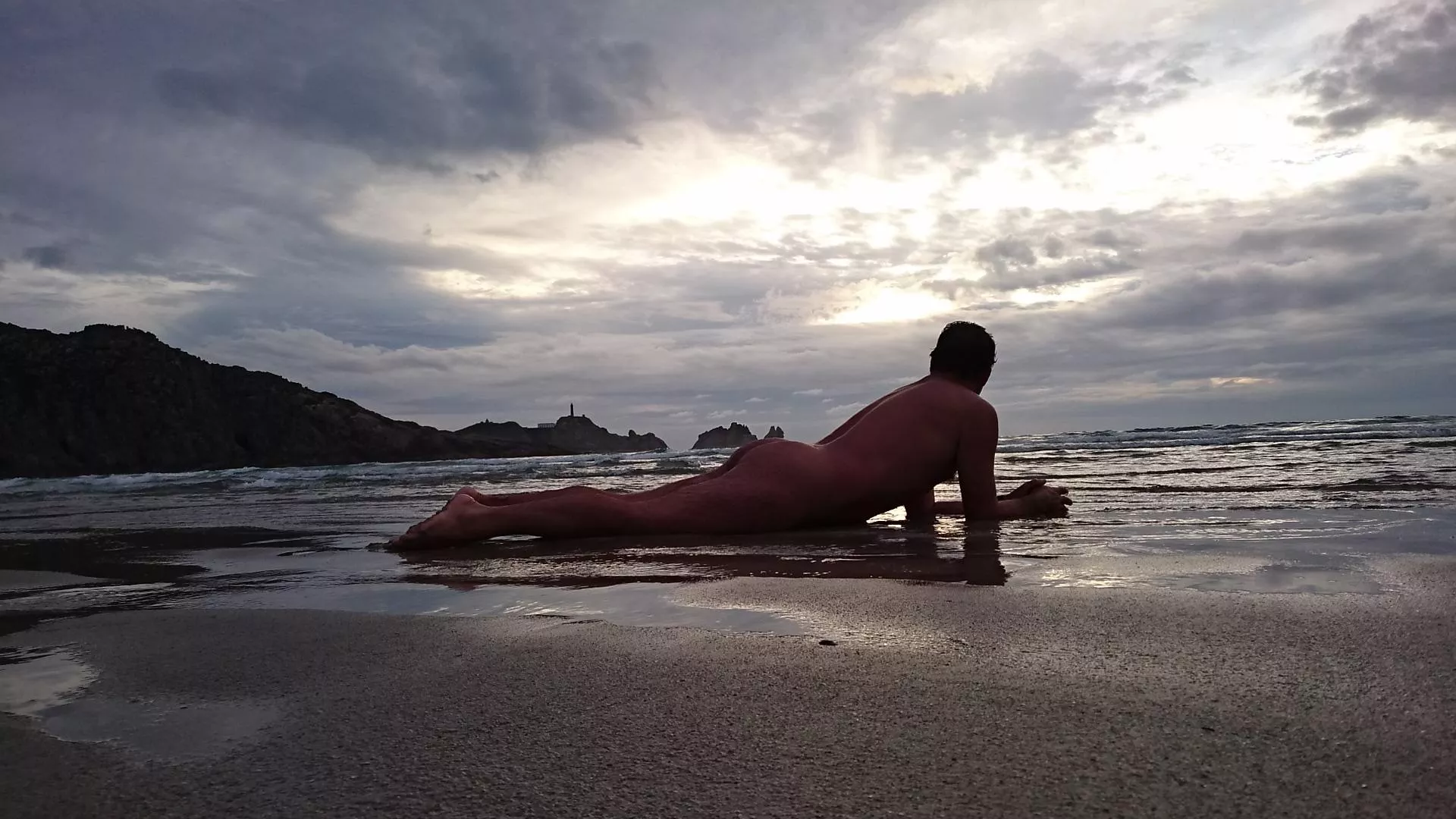 Sunset hunter. Cloudy day at the beach. Nude freedom